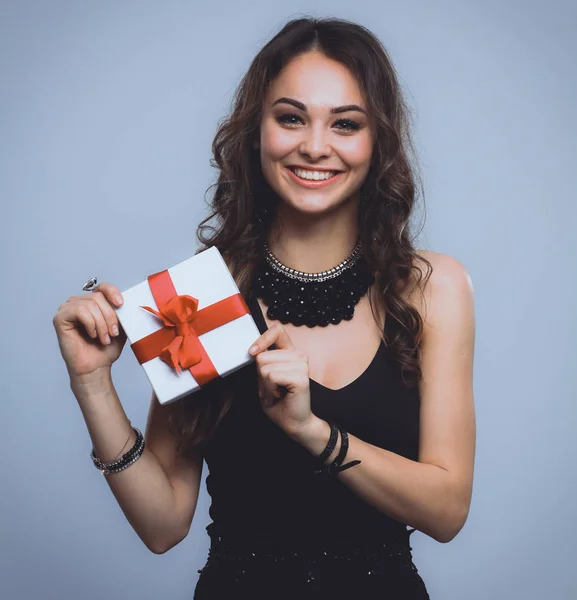 Jeune femme sourire heureux tenir boîte cadeau dans les mains, isolé sur fond gris — Photo