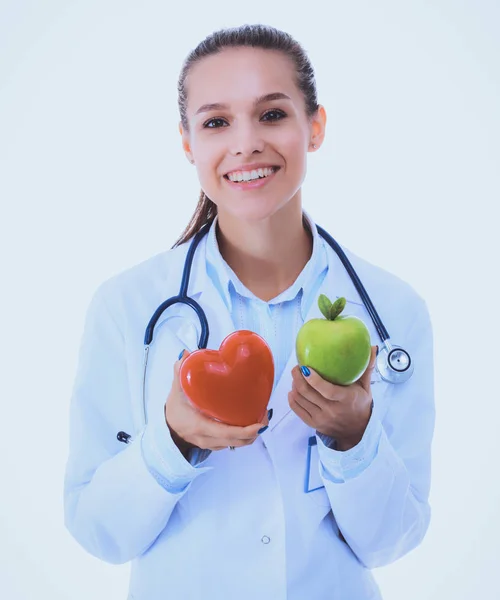 Mooie glimlachende vrouwelijke arts met rood hart en groene appel — Stockfoto