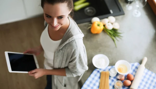 Женщина печет дома по рецепту на планшете — стоковое фото