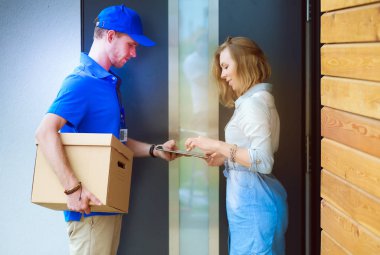 Mavi üniformalı gülümseyen kurye servis konseptine paket kutusu teslim eden teslimatçı. Mavi üniformalı gülümseyen teslimatçı.
