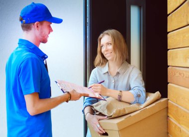 Mavi üniformalı gülümseyen kurye servis konseptine paket kutusu teslim eden teslimatçı. Mavi üniformalı gülümseyen teslimatçı.