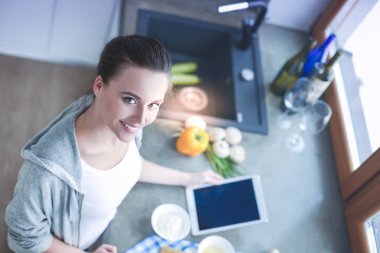 Güzel bir kadın mutfakta pasta pişiriyor. Masanın yanında duruyor..