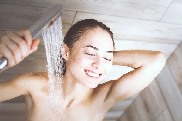 Joven mujer hermosa bajo la ducha en el baño . — Foto de Stock