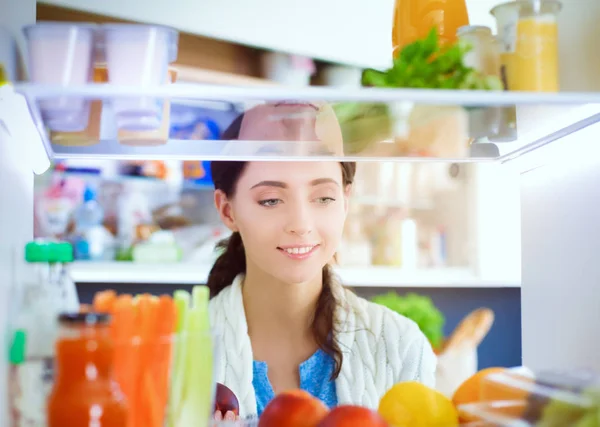 Portrait of female standing near open fridge full of healthy food, vegetables and fruits. Portrait of female — Stock Photo, Image