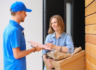 Mavi üniformalı gülümseyen kurye servis konseptine paket kutusu teslim eden teslimatçı. Mavi üniformalı gülümseyen teslimatçı.