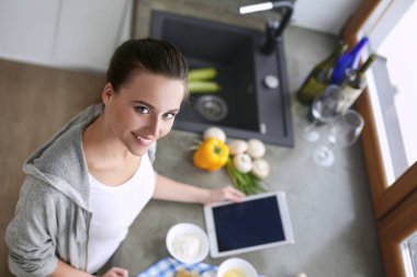 Güzel bir kadın mutfakta pasta pişiriyor. Masanın yanında duruyor..