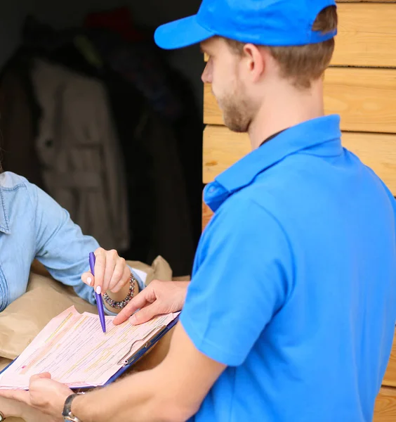 Repartidor sonriente con uniforme azul que entrega la caja de paquetes al destinatario: concepto de servicio de mensajería. Repartidor sonriente en uniforme azul — Foto de Stock