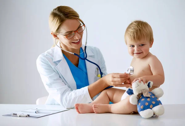 La doctora está escuchando a un niño con un estetoscopio en la clínica — Foto de Stock