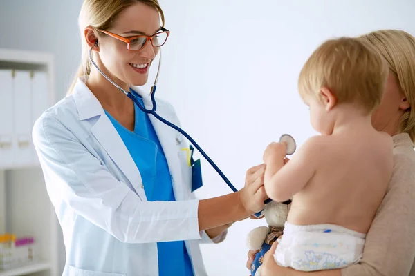 Kobieta lekarz słucha dziecko ze stetoskopem w klinice — Zdjęcie stockowe