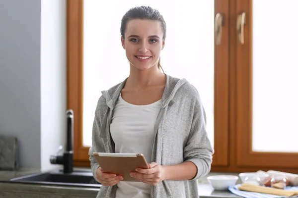 Beautiful woman cooking cake in kitchen standing near desk. — Stock Photo, Image