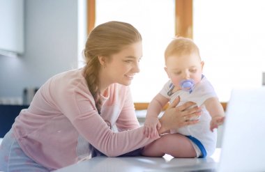 Annesi bebeğini evde parlak mutfakta ile.
