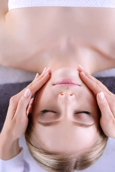 Mujer joven acostada en una mesa de masaje, relajándose con los ojos cerrados. Una mujer. Salón de spa —  Fotos de Stock