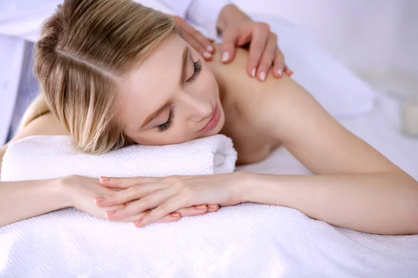 Mujer joven acostada en una mesa de masaje, relajándose con los ojos cerrados. Una mujer. Salón de spa —  Fotos de Stock