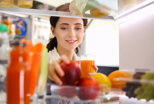 Portrait of female standing near open fridge full of healthy food, vegetables and fruits. Portrait of female — Stock Photo, Image