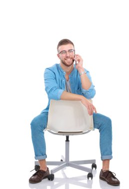 Sandalyede oturan ve cep telefonuyla genç adam. Startupper. Genç girişimci.