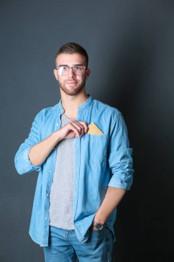 Gri arka planda duran bir kredi kartı tutan genç adam. Genç girişimci..