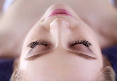 Masaj masasında uzanmış gözleri kapalı rahatlayan genç bir kadın. - Kadın. Spa salonu