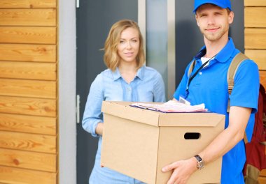 Mavi üniformalı gülümseyen kurye servis konseptine paket kutusu teslim eden teslimatçı. Mavi üniformalı gülümseyen teslimatçı.