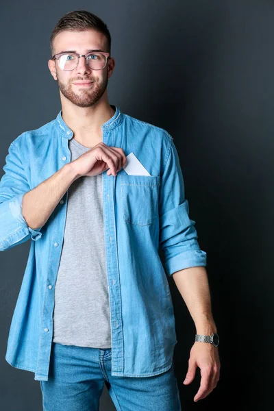 Joven sosteniendo una tarjeta de crédito de pie sobre fondo gris. Joven empresario. —  Fotos de Stock