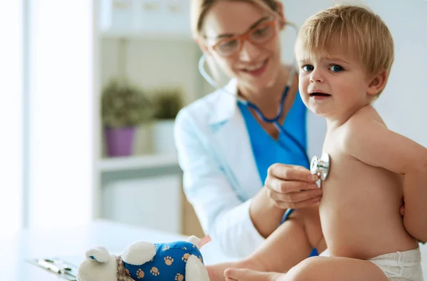 Vrouwelijke arts luistert kind met een stethoscoop in de kliniek — Stockfoto