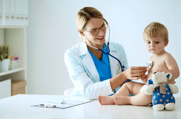 Female doctor is listening kid with a stethoscope in clinic — Stock Photo, Image