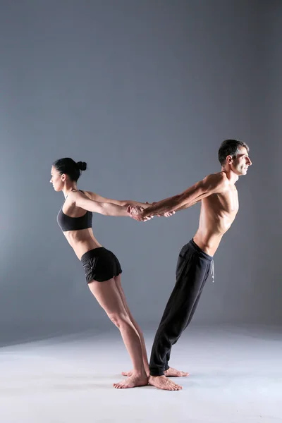 Young couple practicing acro yoga on mat in studio together. Acroyoga. Couple yoga. Partner yoga.