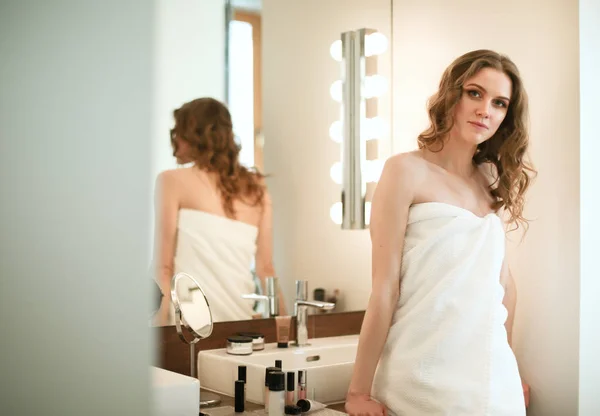 Young woman looking in the mirror and putting make-up on. — Stock Photo, Image