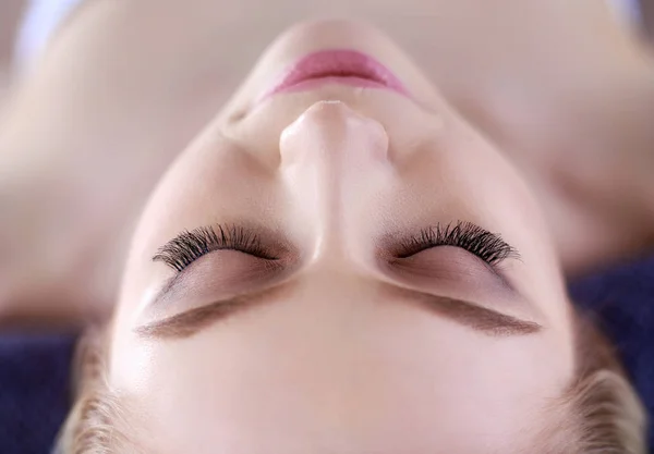 Mujer joven acostada en una mesa de masaje, relajándose con los ojos cerrados. Una mujer. Salón de spa — Foto de Stock