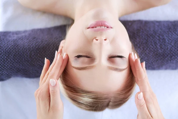 Mujer joven acostada en una mesa de masaje, relajándose con los ojos cerrados. Una mujer. Salón de spa —  Fotos de Stock