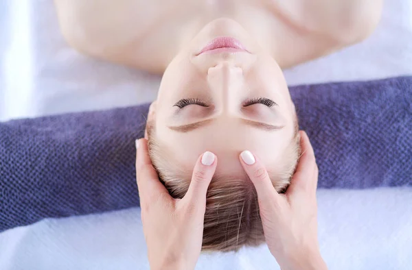 Mujer joven acostada en una mesa de masaje, relajándose con los ojos cerrados. Una mujer. Salón de spa — Foto de Stock