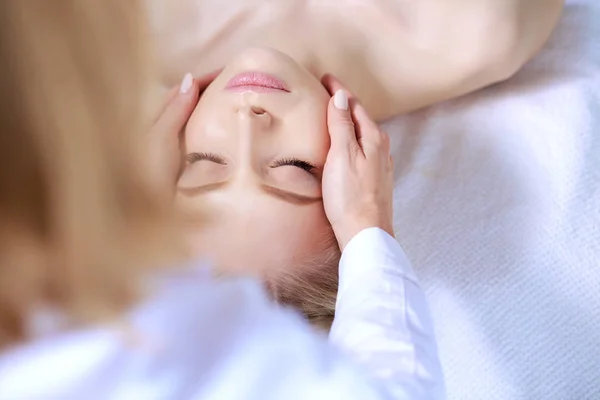 Mujer joven acostada en una mesa de masaje, relajándose con los ojos cerrados. Una mujer. Salón de spa — Foto de Stock