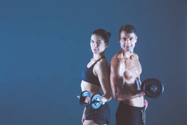 Atletik erkek ve kadın ile bir dumbells. Kişisel fitness eğitmeni. Kişisel eğitim.