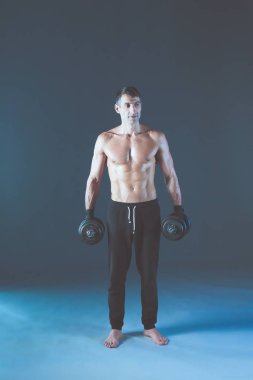 Yakışıklı kaslı adam dumbell ile çalışma dışarı. Kişisel fitness eğitmeni. Kişisel eğitim.