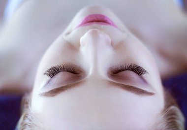 Masaj masasında uzanmış gözleri kapalı rahatlayan genç bir kadın. - Kadın. Spa salonu