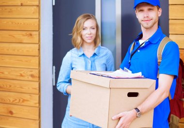Mavi üniformalı gülümseyen kurye servis konseptine paket kutusu teslim eden teslimatçı. Mavi üniformalı gülümseyen teslimatçı.