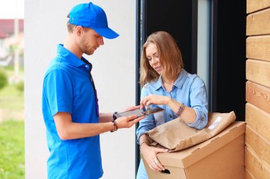 Mavi üniformalı gülümseyen kurye servis konseptine paket kutusu teslim eden teslimatçı. Mavi üniformalı gülümseyen teslimatçı.