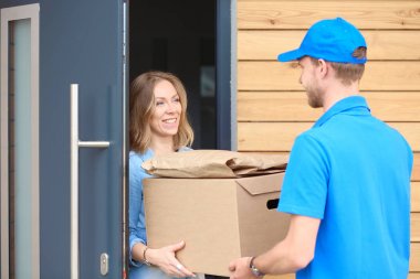 Mavi üniformalı gülümseyen kurye servis konseptine paket kutusu teslim eden teslimatçı. Mavi üniformalı gülümseyen teslimatçı.