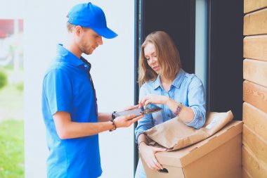 Mavi üniformalı gülümseyen kurye servis konseptine paket kutusu teslim eden teslimatçı. Mavi üniformalı gülümseyen teslimatçı.