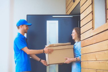 Mavi üniformalı gülümseyen kurye servis konseptine paket kutusu teslim eden teslimatçı. Mavi üniformalı gülümseyen teslimatçı.