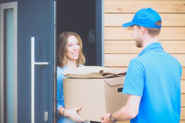 Mavi üniformalı gülümseyen kurye servis konseptine paket kutusu teslim eden teslimatçı. Mavi üniformalı gülümseyen teslimatçı.