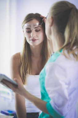 Kaşlar için kalıcı makyaj. Güzellik salonunda kalın kaşlı güzel bir kadın..