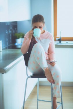 modern mutfakta otururken cep telefonu kullanan kadın.