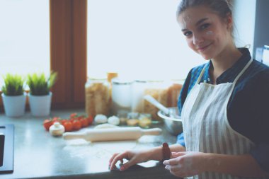 Güzel bir kadın mutfakta pasta pişiriyor. Masanın yanında duruyor..