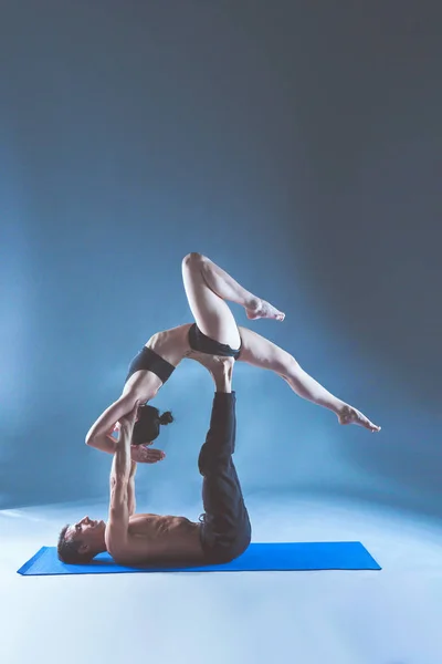 Pareja joven practicando acro yoga en estera en estudio juntos. Acroyoga. Un par de yoga. Socio yoga . —  Fotos de Stock