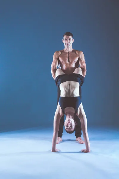 Giovane coppia praticare acro yoga sul tappeto in studio insieme. Acroyoga. Un paio di yoga. Partner yoga . — Foto Stock