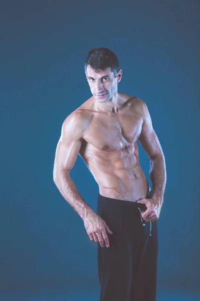 Homem musculado. Homem musculoso sobre um fundo cinzento mostrando músculos. Instrutor de fitness. Profissional de fitness. Treino. Aptidão dos homens . — Fotografia de Stock