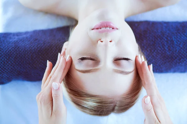 Mujer joven acostada en una mesa de masaje, relajándose con los ojos cerrados. Una mujer. Salón de spa — Foto de Stock