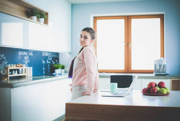 Woman using mobile phone standing in modern kitchen. — Stock Photo, Image
