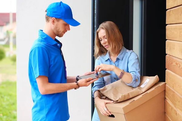 Mavi üniformalı gülümseyen kurye servis konseptine paket kutusu teslim eden teslimatçı. Mavi üniformalı gülümseyen teslimatçı.