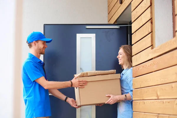 Leende leverans man i blå uniform leverera paket låda till mottagaren - kurir service koncept. Leende leverans man i blå uniform — Stockfoto